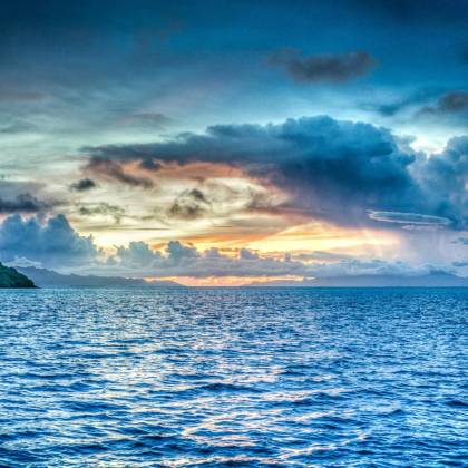 Vibrant Sunset Over Tropical Ocean With Dramatic Clouds And Distant Island.