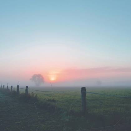 Peaceful Morning Landscape With Fog And Sunrise Over A Fenced Countryside Field.