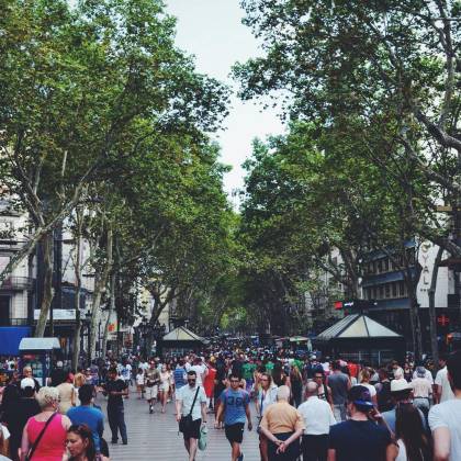 A Vibrant Street Filled With People And Trees, Showcasing Urban Life In Barcelona.
