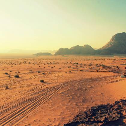 Explore The Stunning Beauty Of Wadi Rum's Arid Desert Landscape, Bathed In Warm Sunset Hues.