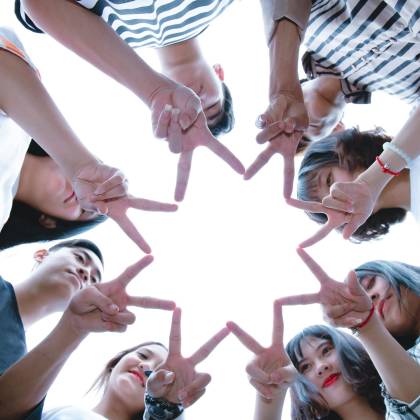 A Circle Of Friends Forming A Star Shape With Fingers, Symbolizing Unity And Teamwork.