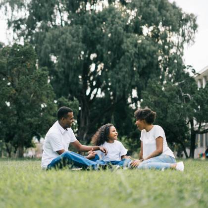 A Happy Black Family Enjoying Quality Time Together Outdoors In A Lush Green Park.