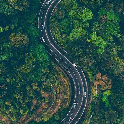 A Sweeping Aerial View Of An S Shaped Road Winding Through Vibrant Green Malaysian Forest.