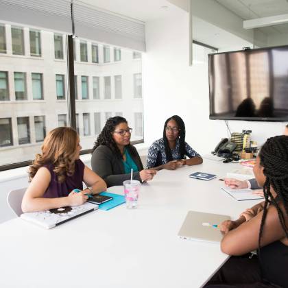 A Group Of Diverse Women Engage In A Business Discussion In A Modern Office Setting.