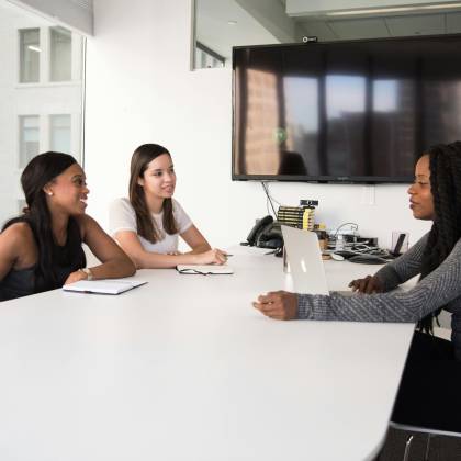 Three Women Collaborate In A Modern Office Setting, Discussing Business Plans And Teamwork.