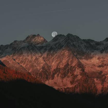 Stunning View Of Mountain Peaks Under Moonlight With A Twilight Glow Creating A Dramatic Landscape.