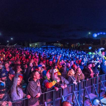 Energetic Crowd Enjoying A Night Concert With Vibrant Lights And Festive Atmosphere.