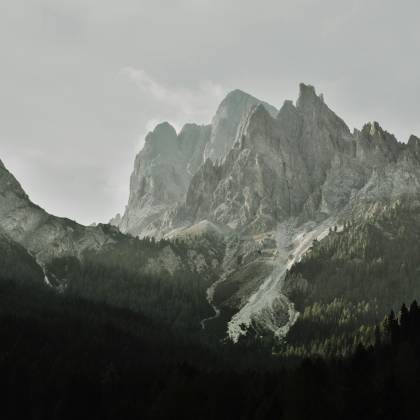Breathtaking View Of Rugged Mountain Peaks With Lush Forest In Foreground, Perfect For Nature Enthusiasts.