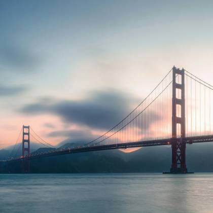 Stunning Sunset View Of The Iconic Golden Gate Bridge In San Francisco Over Calm Ocean Waters.