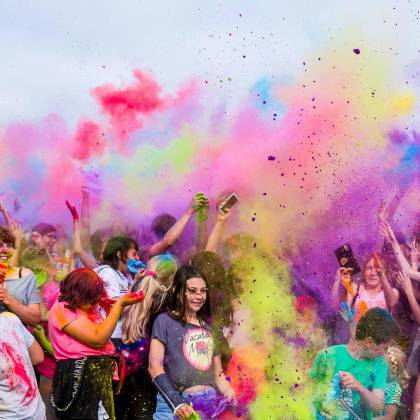 A Joyful Crowd Covered In Vivid Colors Celebrates A Festival Outdoors With Flying Powder.