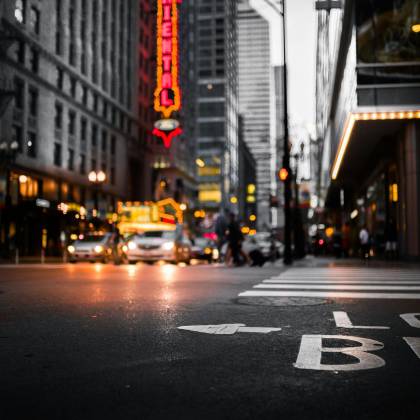 Dynamic Cityscape At Night With Illuminated Signs, Streetlights, And A Bustling Intersection.