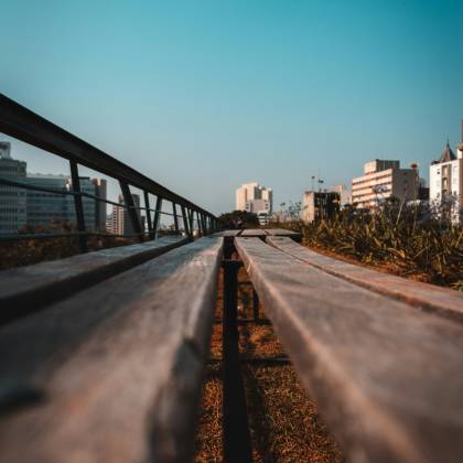 Wooden Pathway Leading Towards A Cityscape Under A Clear Blue Sky, Offering An Urban Perspective.