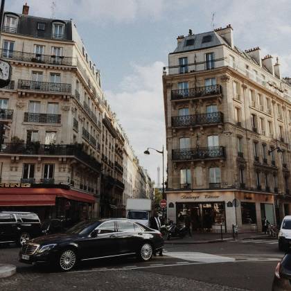 A Bustling Street Corner In Paris Featuring Classic Architecture And Urban Vibe.