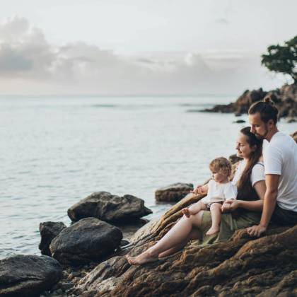 A Serene Family Moment By The Seaside, Capturing Love And Relaxation At Sunset.