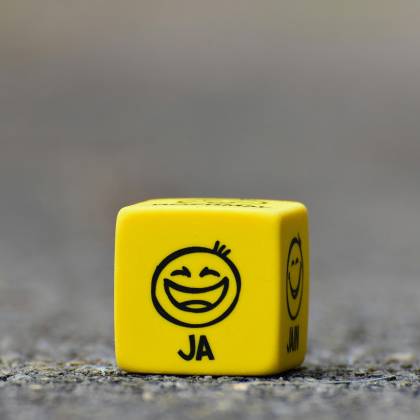 Close Up Of A Yellow Dice Featuring A Smiley Face Emoticon Symbolizing Happiness And Fun.
