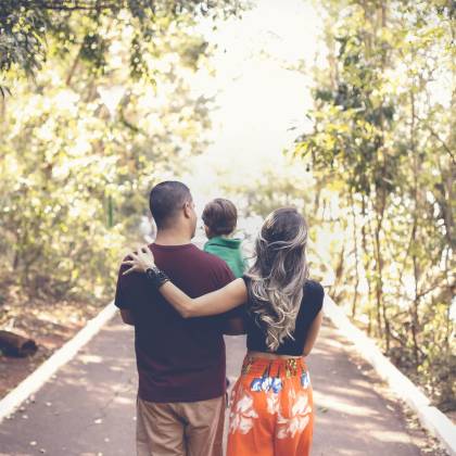 A Family Enjoying A Leisurely Walk On A Sunny Park Trail, Showcasing Togetherness And Love.