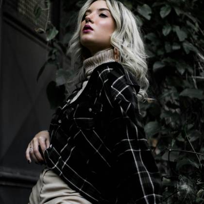 Stylish Woman Posing Outdoors In Plaid Jacket And Beige Sweater.