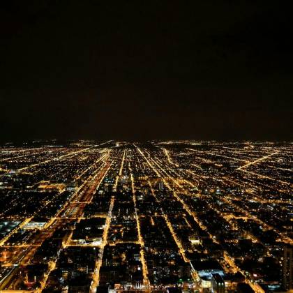 A Breathtaking Aerial View Of A Sprawling City Illuminated By Glowing Lights Against The Night Sky.