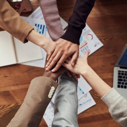 Diverse Professionals Unite For Teamwork Around A Wooden Table With Laptops And Documents.