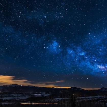 A Breathtaking View Of The Milky Way Galaxy Illuminating The Night Sky Over Mountains.