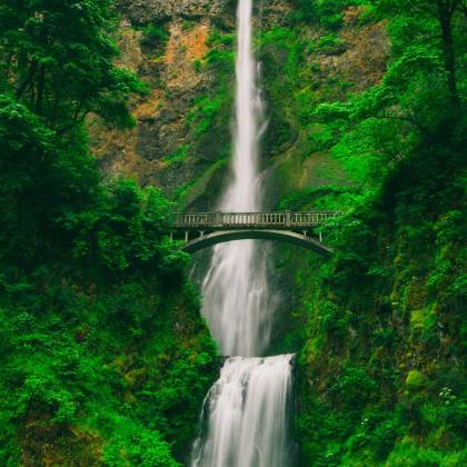 Captivating Waterfall Cascading Through Lush Greenery And A Scenic Bridge.