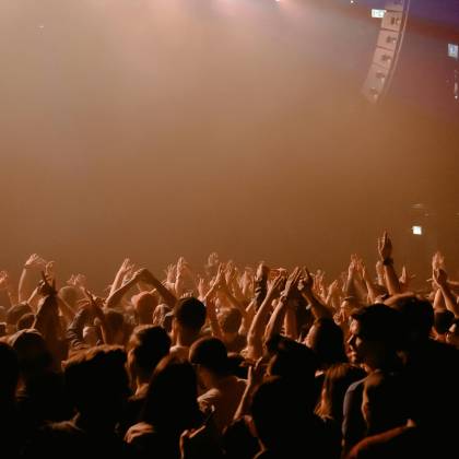 A Lively Crowd Cheering And Dancing At A Nocturnal Music Performance In A Dimly Lit Nightclub.