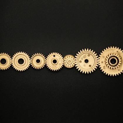 An Artistic Arrangement Of Golden Gears On A Dark Backdrop, Symbolizing Mechanics And Cooperation.