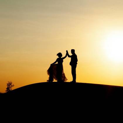 Silhouetted Couple Dancing On The Beach During A Golden Sunset, Creating A Romantic Scene.