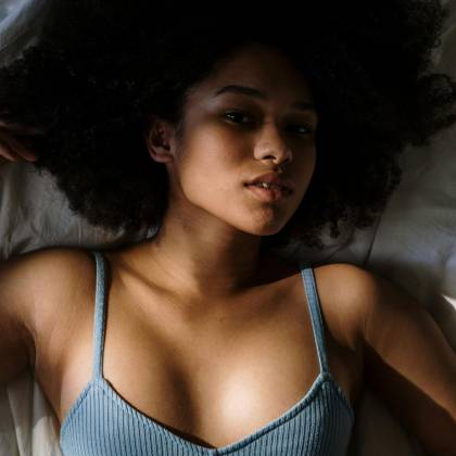 Beautiful Woman With Curly Hair Resting In Bed, Enjoying Morning Light.