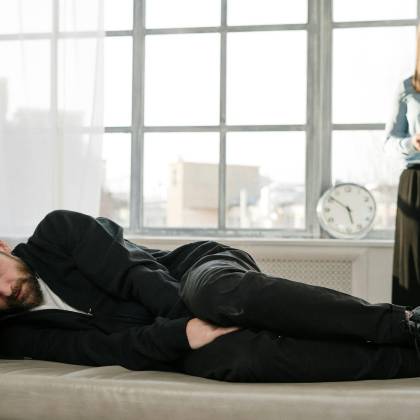 Psychological Therapy Session With A Male Patient Lying On A Couch And A Female Therapist Taking Notes.