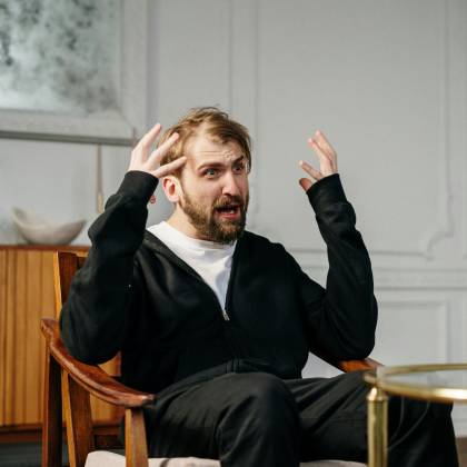 A Man In A Therapy Session Expressing Emotions, Seated Indoors At A Modern Office.