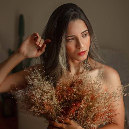 Woman Poses Indoors Holding A Bouquet Of Dried Flowers, Capturing A Warm And Intimate Mood.