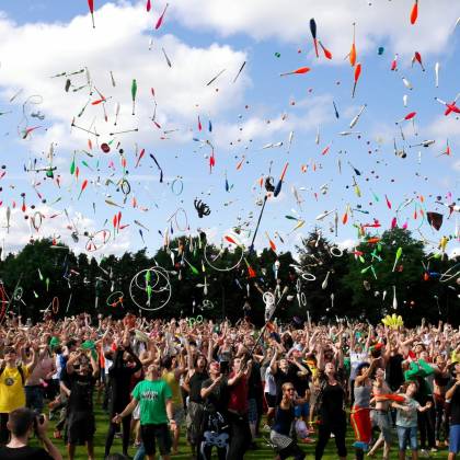 A Lively Crowd Enjoying A Colorful Juggling Event Outdoors. Perfect For Summer Festival Themes.