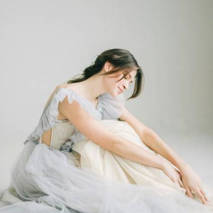 Graceful Woman Poses In Soft Light Wearing A Flowing Dress. Ideal For Fashion And Lifestyle Imagery.