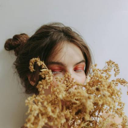 Serene Portrait Of A Woman Partially Obscured By Dried Flowers, Capturing A Moment Of Tranquility And Soft Elegance.
