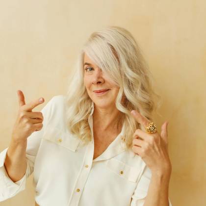 Elegant Senior Woman With White Hair Smiling And Posing Confidently Against A Neutral Background.