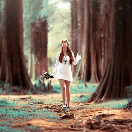 A Young Woman In A White Dress Enjoys A Leisure Walk In A Serene Forest Setting.
