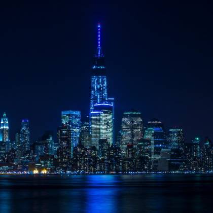 Illuminated New York City Skyline Reflecting Over The Hudson River At Night.