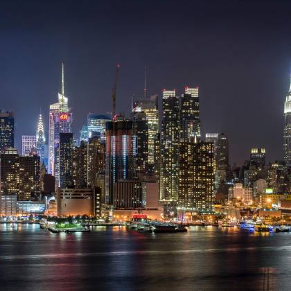 Stunning View Of The Illuminated New York City Skyline Reflecting On The Hudson River At Night.