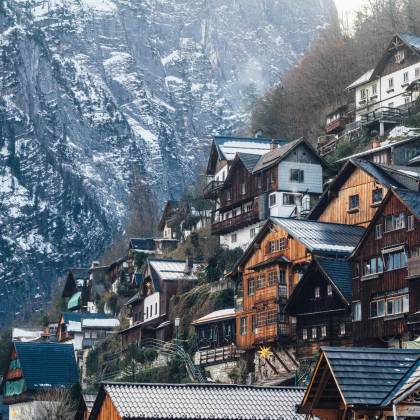 Charming Wooden Homes Nestled On A Snowy Cliffside In Liezen, Austria, During Winter.