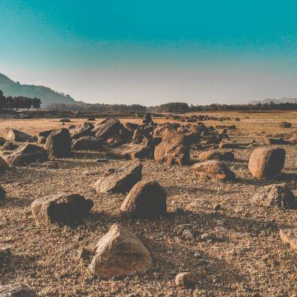 A Beautiful Arid Desert Landscape With Scattered Rocks Under A Clear Blue Sky.